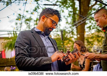 Two men at garden party, looking at smartphone View Large Photo Image Stock Image - Two men at garden party, looking at smartphone. Fotosearch
