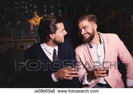 Two men at party, holding drinks, laughing View Large Photo Image Stock Photograph - Two men at party, holding drinks, laughing. Fotosearch