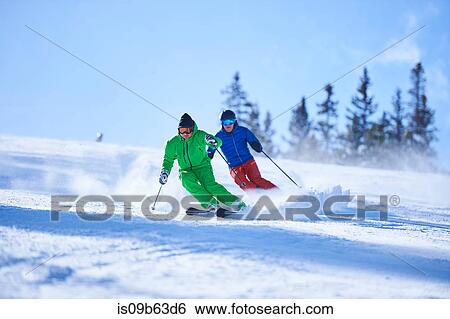 Stock Photograph - Two men skiing down snow covered ski slope, Aspen, Colorado, USA. Fotosearch