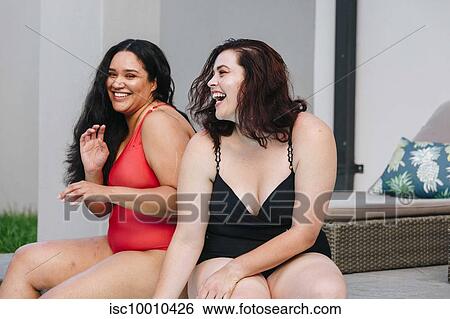 Two mid adult women sitting on outdoor pool side laughing together, Cape Town, South Africa View Large Photo Image Stock Photograph - Two mid adult women sitting on outdoor pool side laughing together, Cape Town, South Africa. Fotosearch