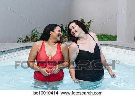 Two mid adult women standing in outdoor swimming pool laughing together, Cape Town, South Africa View Large Photo Image Picture - Two mid adult women standing in outdoor swimming pool laughing together, Cape Town, South Africa. Fotosearch