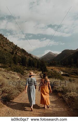 Two woman in maxi dresses strolling on rural valley road, rear view, Mineral King, California, USA View Large Photo Image Stock Photo - Two woman in maxi dresses strolling on rural valley road, rear view, Mineral King, California, USA. Fotosearch