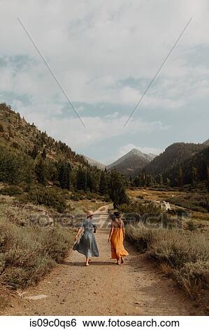 Two woman in maxi dresses strolling on rural valley road, rear view, Mineral King, California, USA View Large Photo Image Stock Photograph - Two woman in maxi dresses strolling on rural valley road, rear view, Mineral King, California, USA. Fotosearch