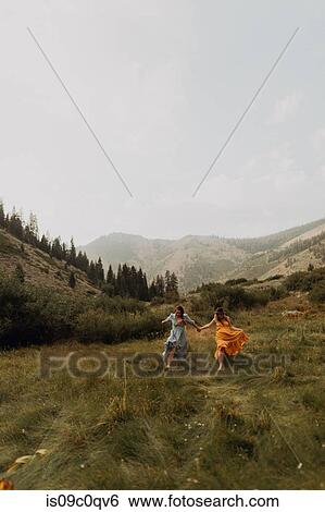 Two women holding hands running in rural valley, Mineral King, California, USA View Large Photo Image Stock Photograph - Two women holding hands running in rural valley, Mineral King, California, USA. Fotosearch