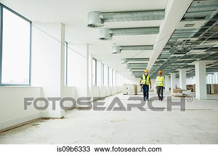 Two workers wearing hi vis vests, walking through newly constructed office space View Large Photo Image Stock Image - Two workers wearing hi vis vests, walking through newly constructed office space. Fotosearch