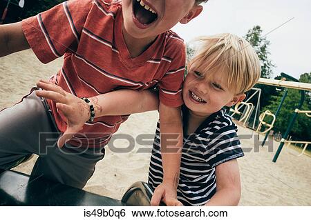 Stock Photograph - Two young boys playing outdoors, laughing. Fotosearch