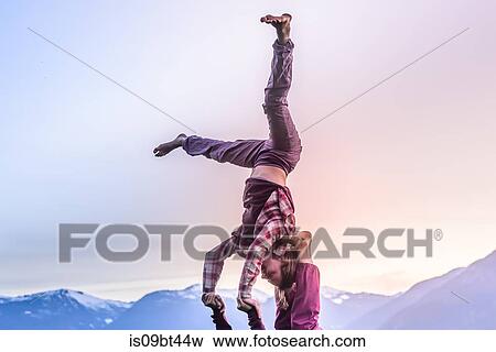 Two young women 0acticing acroyoga in front of mountain range at sunset, Squamish, British Columbia, Canada View Large Photo Image Stock Photo - Two young women 0acticing acroyoga in front of mountain range at sunset, Squamish, British Columbia, Canada. Fotosearch