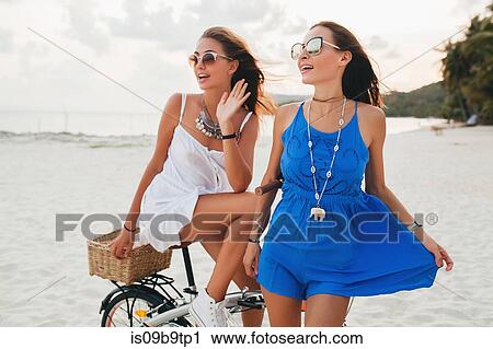 Two young women in sundresses with bicycle on sandy beach, Krabi, Thailand View Large Photo Image Stock Image - Two young women in sundresses with bicycle on sandy beach, Krabi, Thailand. Fotosearch