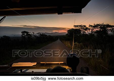 Stock Image - View from vehicle of road ahead at dusk, Kruger National Park, South Africa. Fotosearch