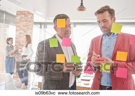 View through glass of colleagues brainstorming using sticky notes View Large Photo Image Stock Image - View through glass of colleagues brainstorming using sticky notes. Fotosearch