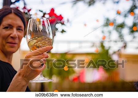Woman at garden party, holding glass of wine, raising glass View Large Photo Image Picture - Woman at garden party, holding glass of wine, raising glass. Fotosearch
