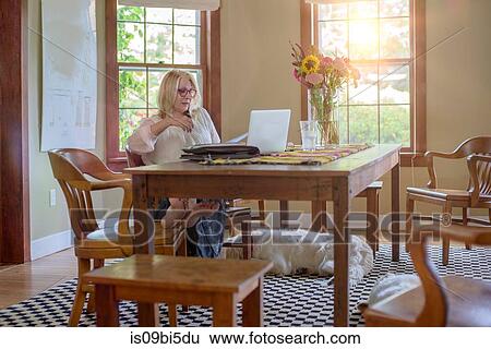 Woman at table using laptop computer View Large Photo Image Stock Photograph - Woman at table using laptop computer. Fotosearch