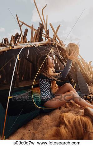 Stock Photo - Woman by tent happy with her collection of coconuts, Princeville, Hawaii, US. Fotosearch