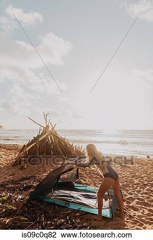 Stock Image - Woman camping on sandy beach, Princeville, Hawaii, US. Fotosearch