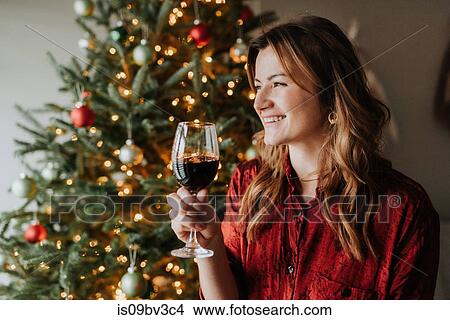 Woman drinking wine beside decorated Christmas tree View Large Photo Image Picture - Woman drinking wine beside decorated Christmas tree. Fotosearch