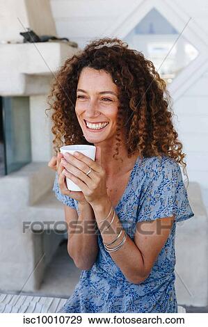 Woman enjoying hot drink clasped in hands at home View Large Photo Image Stock Photo - Woman enjoying hot drink clasped in hands at home. Fotosearch