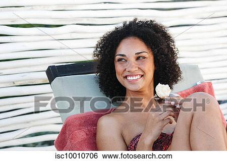 Woman enjoying ice cream on deckchair View Large Photo Image Stock Photograph - Woman enjoying ice cream on deckchair. Fotosearch