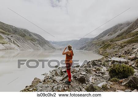 Stock Image - Woman enjoying scenic view by lake, Wanaka, Taranaki, New Zealand. Fotosearch