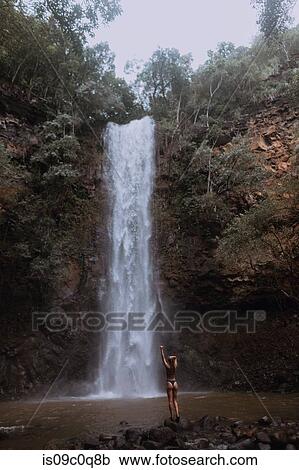 Stock Image - Woman enjoying waterfall, Princeville, Hawaii, US. Fotosearch
