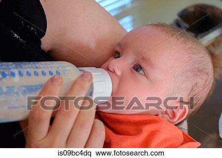 Woman feeding baby boy bottle of milk View Large Photo Image Stock Photography - Woman feeding baby boy bottle of milk. Fotosearch