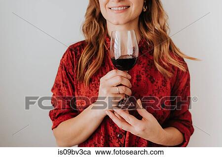 Stock Image - Woman holding glass of wine, white background. Fotosearch