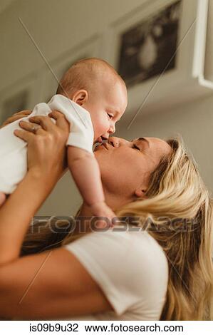 Woman holding up and kissing baby daughter View Large Photo Image Stock Image - Woman holding up and kissing baby daughter. Fotosearch