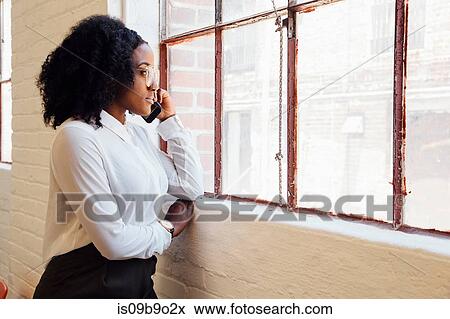 Stock Photo - Woman in industrial office building making telephone call on smartphone. Fotosearch