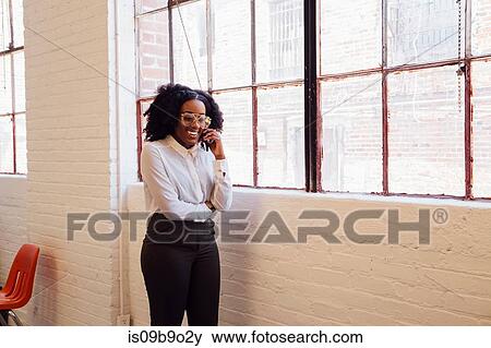 Stock Photo - Woman in industrial office building making telephone call on smartphone. Fotosearch