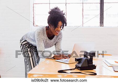 Stock Photograph - Woman in industrial office building using laptop. Fotosearch
