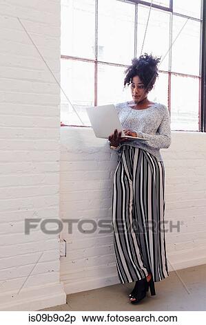 Stock Photography - Woman in industrial office building using laptop. Fotosearch