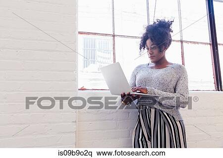 Stock Photography - Woman in industrial office building using laptop. Fotosearch