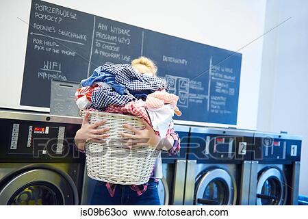 Woman in laundrette carrying full laundry basket View Large Photo Image Picture - Woman in laundrette carrying full laundry basket. Fotosearch