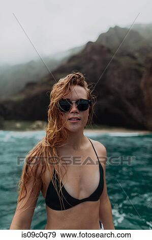 Woman in sunglasses and bikini by seaside, mountains in background, Princeville, Hawaii, US View Large Photo Image Stock Photo - Woman in sunglasses and bikini by seaside, mountains in background, Princeville, Hawaii, US. Fotosearch