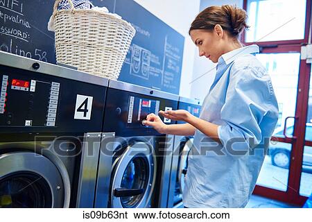 Woman inserting coins into washing machine at laundrette View Large Photo Image Stock Photograph - Woman inserting coins into washing machine at laundrette. Fotosearch