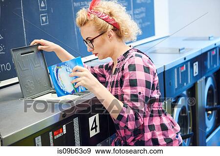 Woman inserting washing powder into washing machine at laundrette View Large Photo Image Stock Photo - Woman inserting washing powder into washing machine at laundrette. Fotosearch