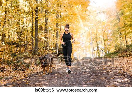 Woman jogging with dog in forest View Large Photo Image Stock Photograph - Woman jogging with dog in forest. Fotosearch