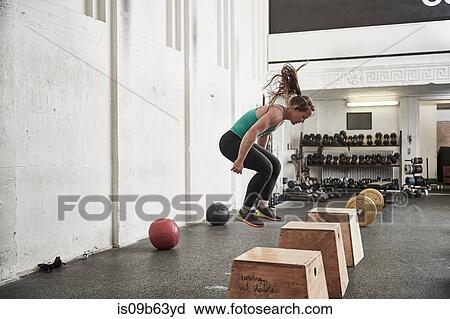 Woman jumping onto fitness box in cross training gym View Large Photo Image Stock Image - Woman jumping onto fitness box in cross training gym. Fotosearch