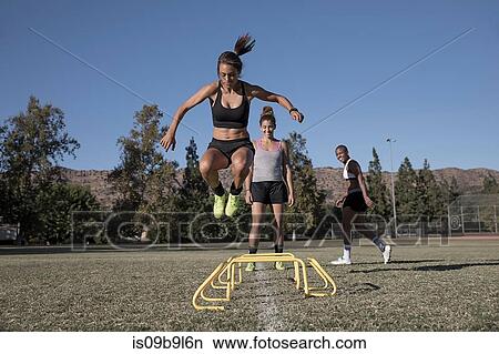 Picture - Woman jumping over agility hurdles. Fotosearch