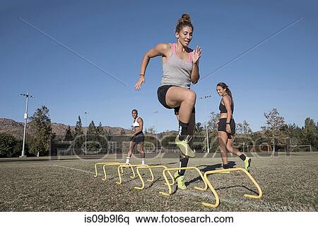 Stock Photography - Woman jumping over agility hurdles. Fotosearch