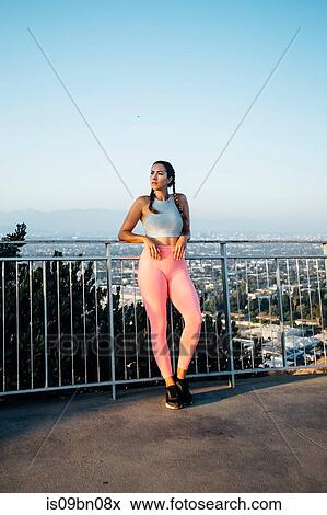 Stock Photo - Woman leaning against railings on hilltop, Los Angeles, US. Fotosearch