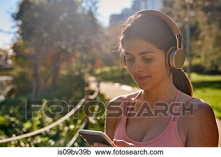 Woman listening to music with headphones in city park View Large Photo Image Stock Image - Woman listening to music with headphones in city park. Fotosearch