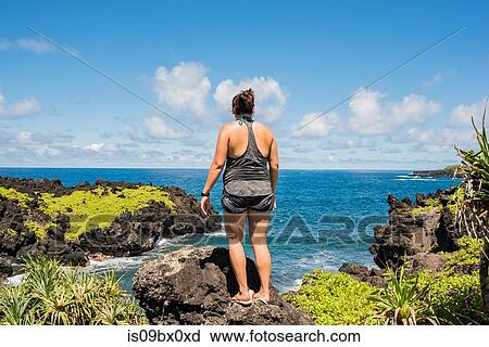 Stock Image - Woman looking at sea, Waianapanapa State Park, Maui, Hawaii. Fotosearch
