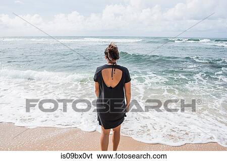 Stock Photograph - Woman looking out to sea, Kapaa Beach, Kauai, Hawaii. Fotosearch