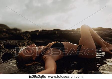 Woman lying on rocks by seaside, Princeville, Hawaii, US View Large Photo Image Stock Image - Woman lying on rocks by seaside, Princeville, Hawaii, US. Fotosearch