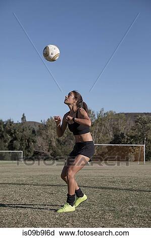 Stock Image - Woman on football pitch playing football. Fotosearch