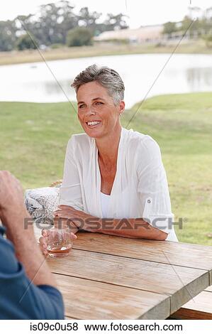 Stock Photo - Woman on garden bench listening to companion, Cape Town, South Africa. Fotosearch