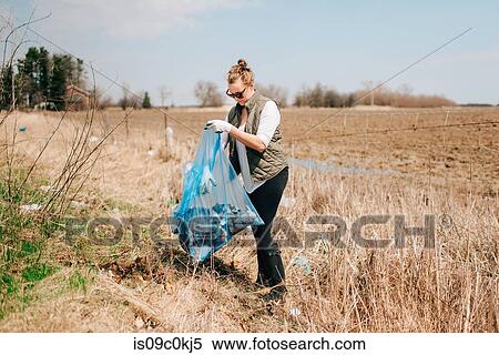Woman picking up rubbish by field, Georgetown, Canada View Large Photo Image Stock Photography - Woman picking up rubbish by field, Georgetown, Canada. Fotosearch