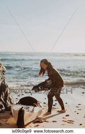 Stock Photo - Woman placing flippers into kayak on beach, Big Sur, California, United States. Fotosearch