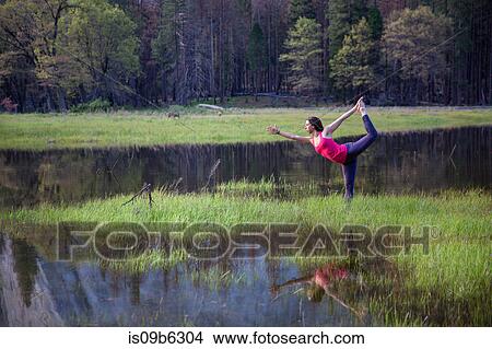 Woman practicing yoga tree pose by lake in Yosemite National Park, California, USA View Large Photo Image Picture - Woman practicing yoga tree pose by lake in Yosemite National Park, California, USA. Fotosearch