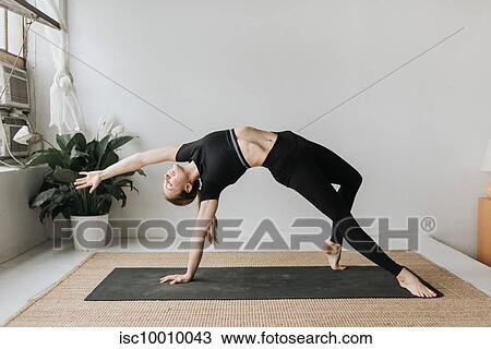 Stock Image - Woman practising yoga in studio. Fotosearch